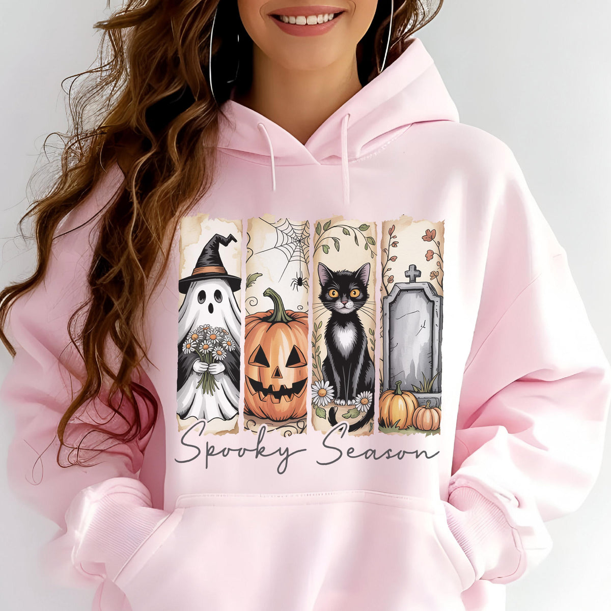 May include: A light pink hooded sweatshirt featuring a graphic print of four vertical panels with a ghost holding flowers, a jack-o'-lantern, a black cat, and a tombstone. The text Spooky Season is printed in a cursive font below the panels.