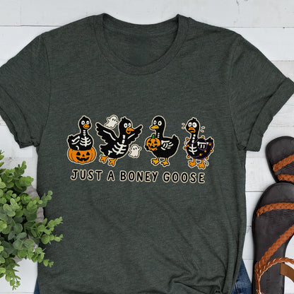 May include: Dark gray t-shirt featuring a Halloween-themed graphic. The design includes four cartoon geese with skeleton-like bodies, pumpkins, and ghosts. The text "JUST A BONEY GOOSE" is printed below the geese in a playful font.