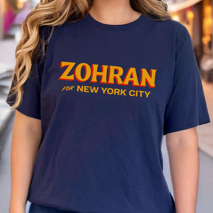 May include: A navy blue short-sleeve t-shirt featuring the text ZOHRAN in large yellow letters with a red drop shadow, followed by the text FOR NEW YORK CITY in smaller yellow letters centered on the chest of the garment.