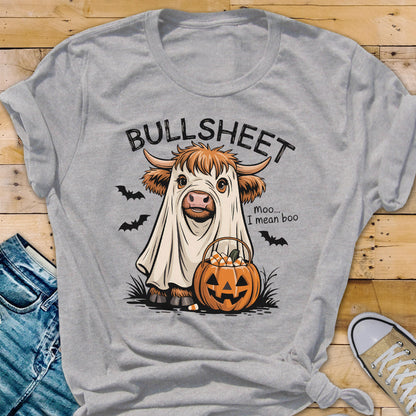 May include: A heather gray t-shirt featuring a Halloween-themed graphic. The design includes a cow dressed as a ghost with the text "BULLSHEET" above and "moo... I mean boo" below. A jack-o'-lantern and bats complete the design.