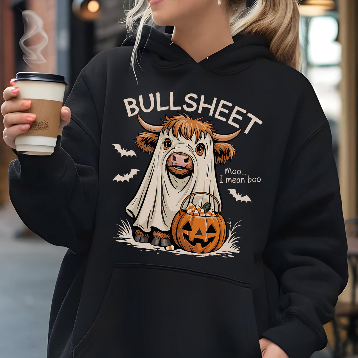 May include: Black hoodie featuring a Halloween-themed graphic. The design includes a cow dressed as a ghost with the text "BULLSHEET" above and "Moo... I mean boo" below. A jack-o'-lantern and bats complete the spooky design.