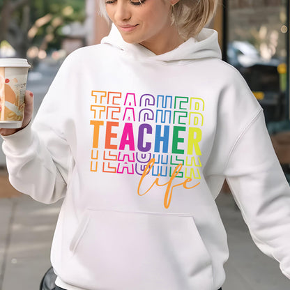 May include: White hoodie with a front pocket and a drawstring hood. The front of the hoodie features the words "TEACHER" stacked vertically in rainbow colors, with "life" in a cursive font below.
