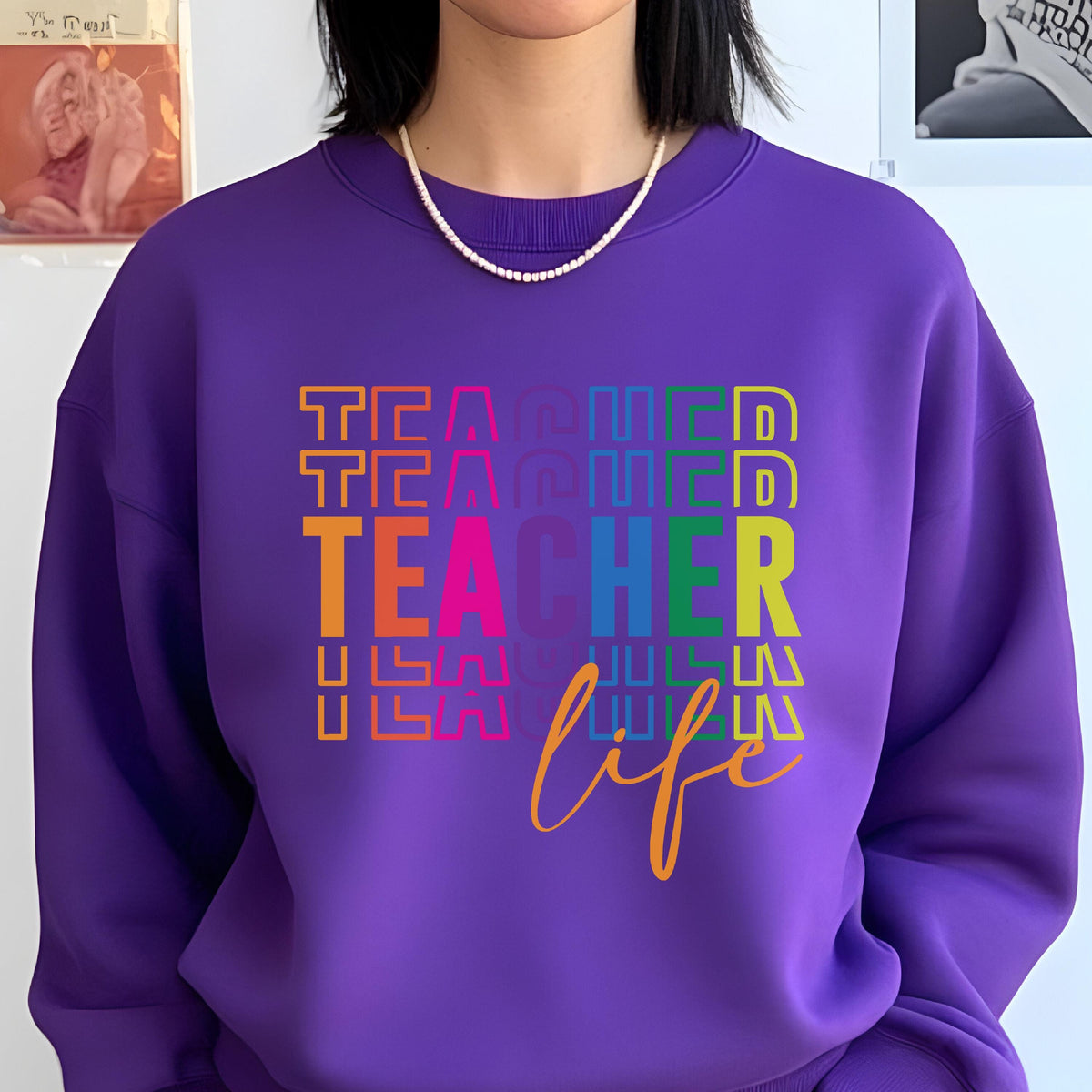 May include: A purple sweatshirt with the word "TEACHER" stacked vertically in a rainbow of colors, with the word "life" in cursive below. The sweatshirt has a crew neck and is made of a soft material.