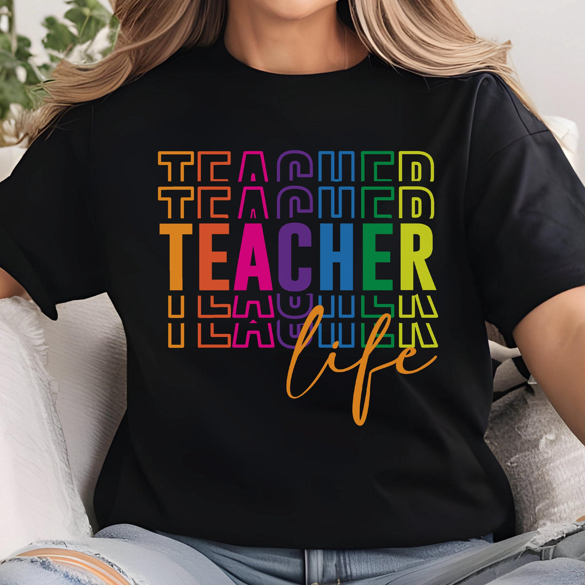 May include: Black t-shirt with the word "TEACHER" in large, colorful letters. The word "TEACHER" is stacked vertically with the word "life" in cursive below it. The design is in rainbow colors.