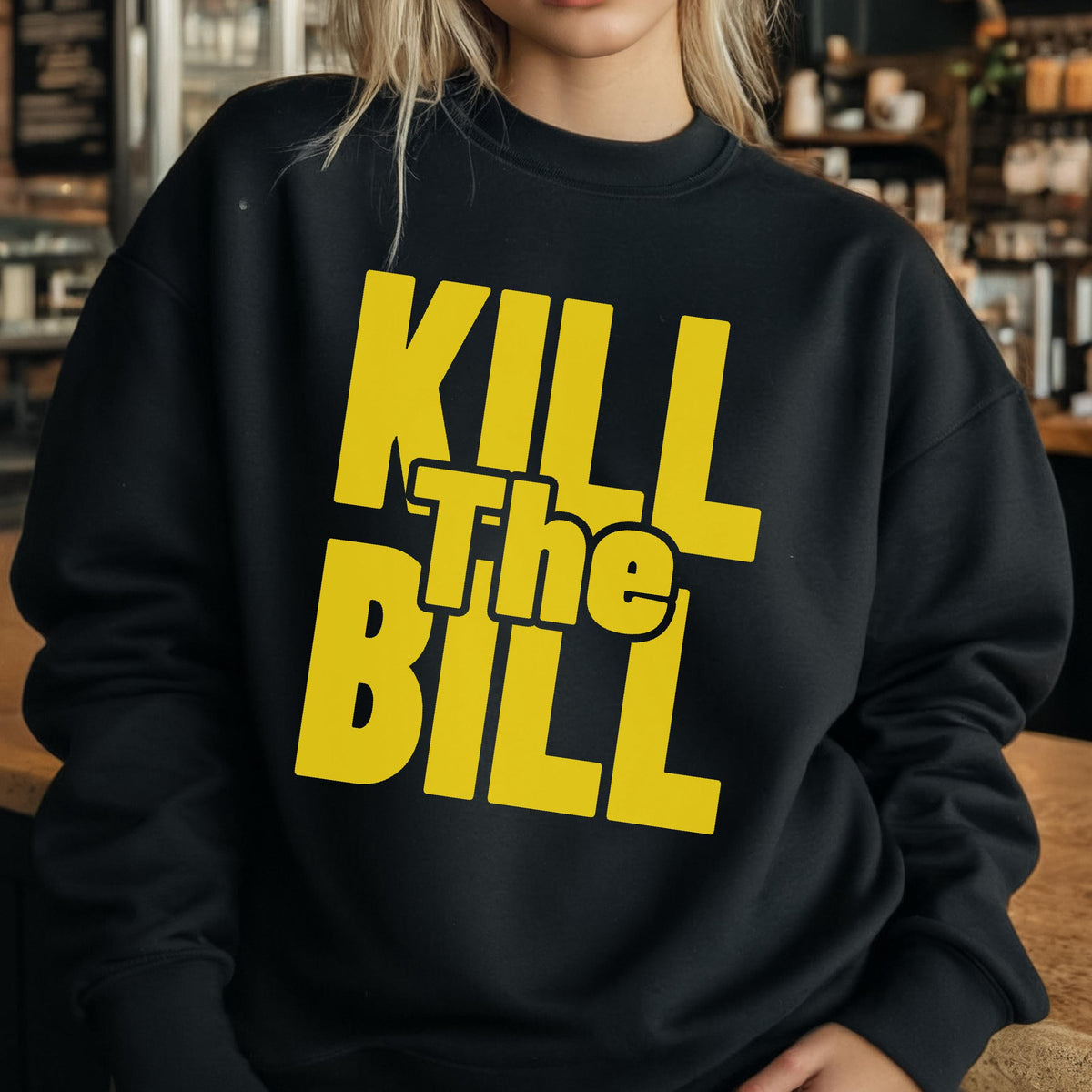 May include: Black sweatshirt with the text "KILL The BILL" in bold yellow letters. The sweatshirt has a crew neck and long sleeves. The text is centered on the front of the garment.