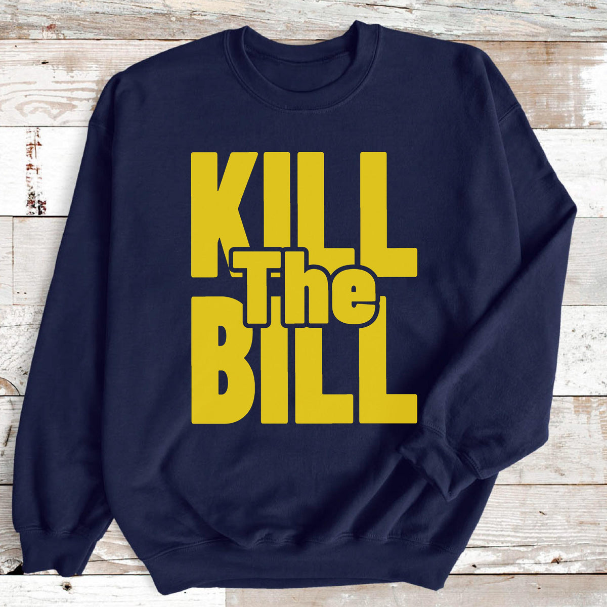 May include: Navy blue sweatshirt with the words "KILL The BILL" in bold, yellow block letters. The text is centered on the front of the long-sleeved garment. The sweatshirt is made of a soft material.