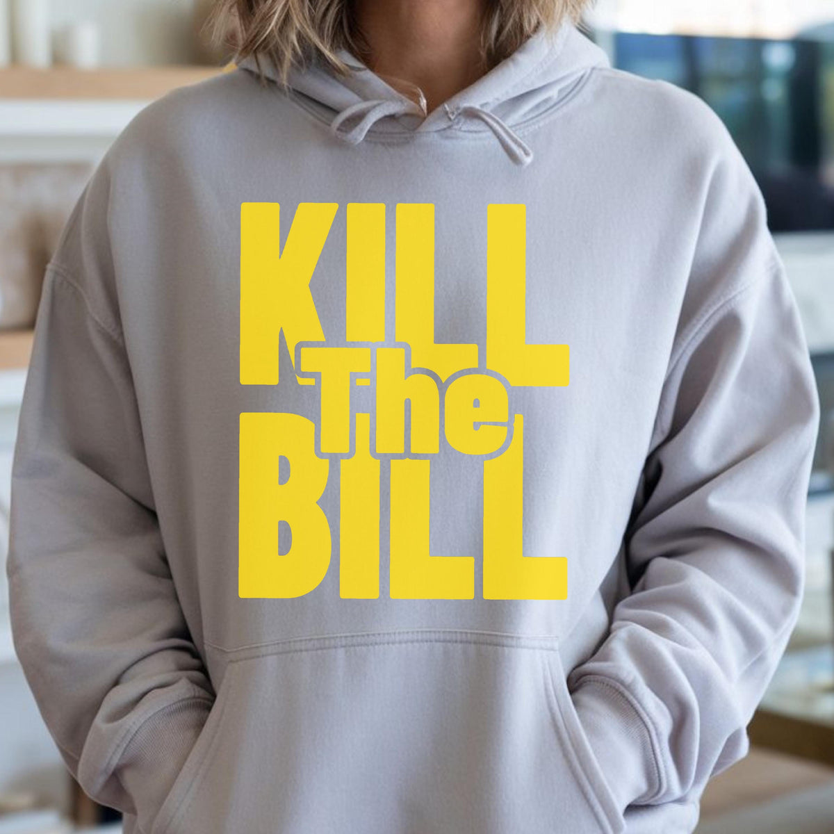 May include: A light gray hoodie with a yellow graphic that reads "KILL The BILL". The hoodie has a drawstring hood and a front pocket. The text is in a bold, sans-serif font.