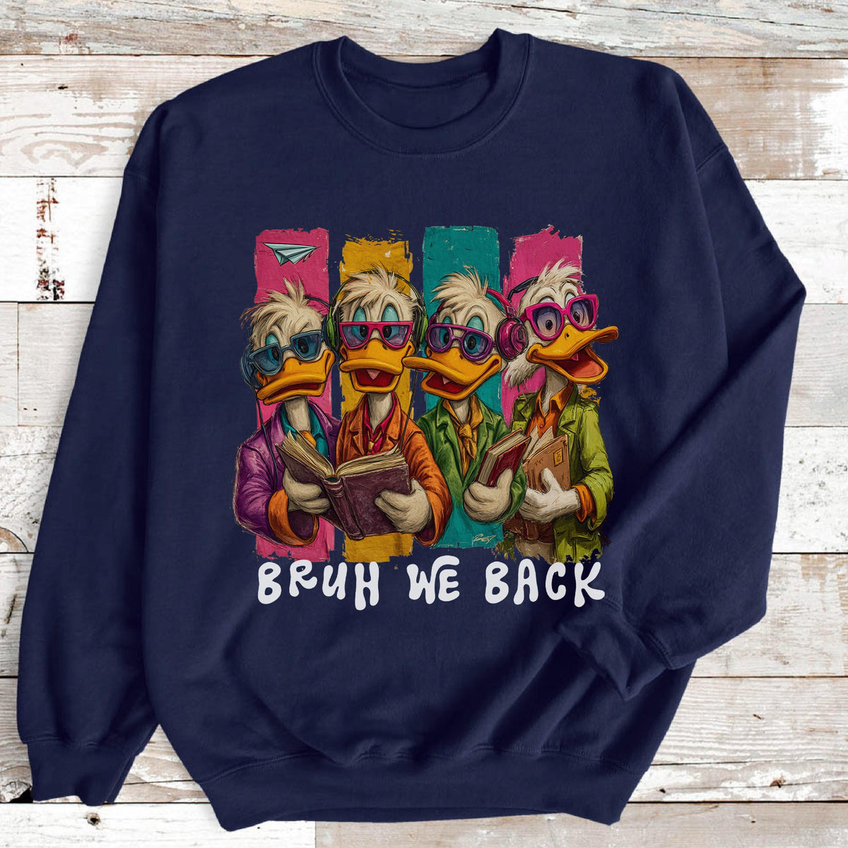 May include: Navy blue sweatshirt featuring a cartoon illustration of four ducks wearing glasses and holding books. The ducks are set against colorful vertical stripes. The text "BRUH WE BACK" is printed below the illustration.