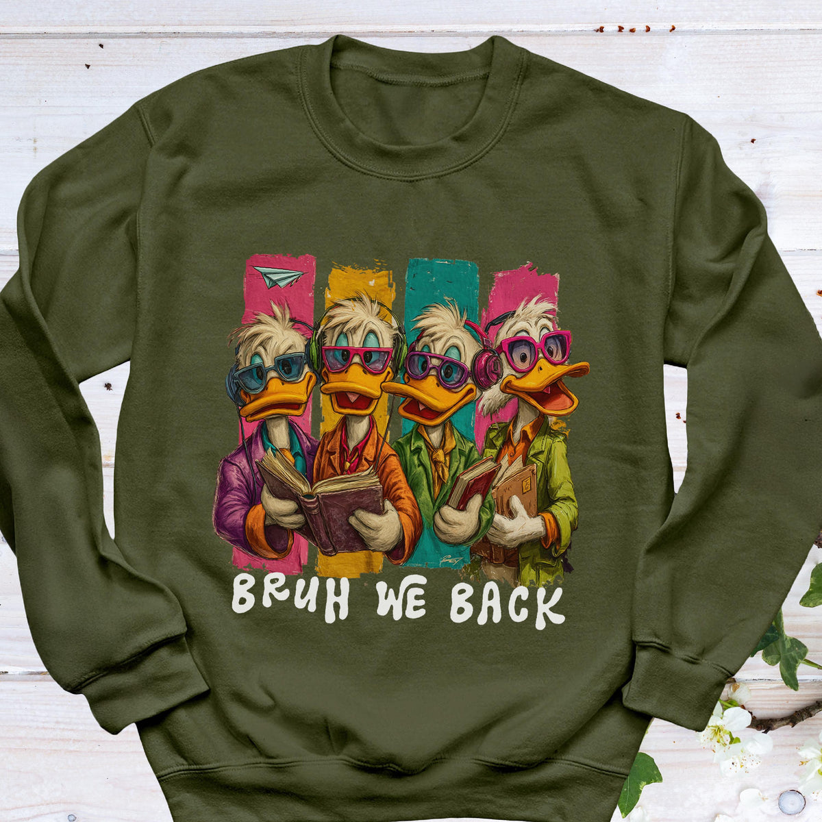 May include: An olive green sweatshirt featuring a cartoon illustration of four ducks wearing glasses and holding books. The ducks are set against colorful vertical stripes, with the text "BRUH WE BACK" in white.