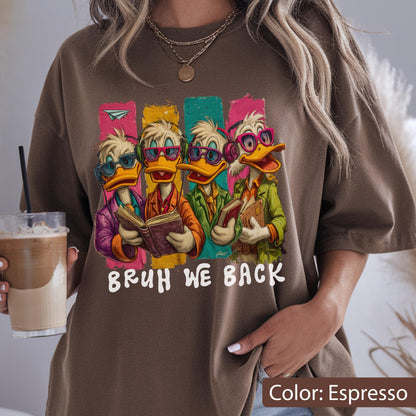 May include: Espresso-colored t-shirt featuring a graphic of four cartoon ducks wearing glasses and reading books. The ducks are set against colorful vertical stripes. The text "BRUH WE BACK" is printed below the ducks.