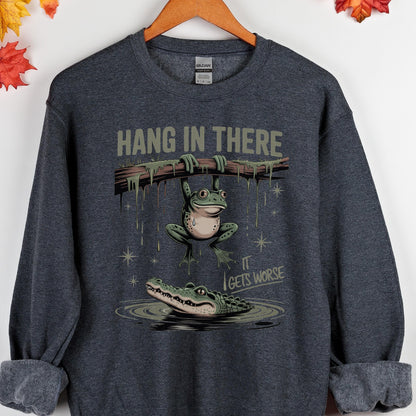 May include: Dark gray sweatshirt with a humorous graphic. The design features a frog hanging from a branch with the text "HANG IN THERE" above and an alligator below with the text "IT GETS WORSE".