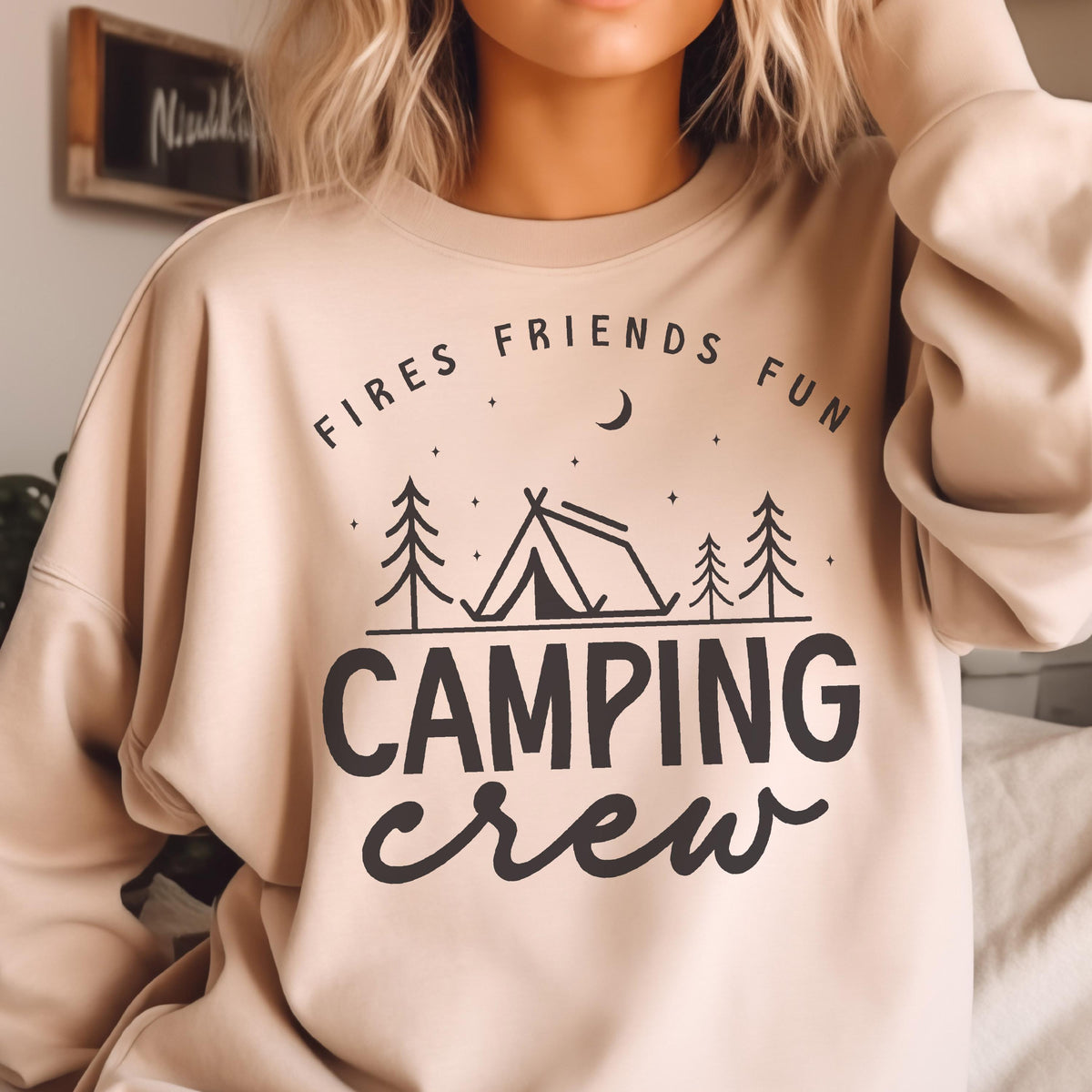 May include: Beige sweatshirt with the words "Fires Friends Fun" above a tent and trees graphic, with "Camping Crew" below. The design is in black. The sweatshirt is a neutral color.