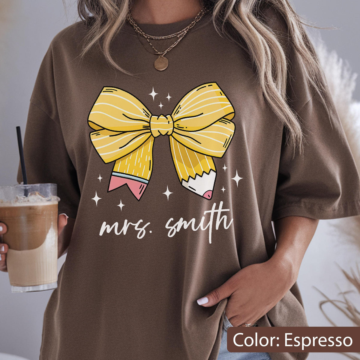 May include: Espresso-colored t-shirt featuring a large yellow bow with pencil accents and the text "mrs. smith" in white script. The bow design includes pink and white details. The shirt is a casual style.