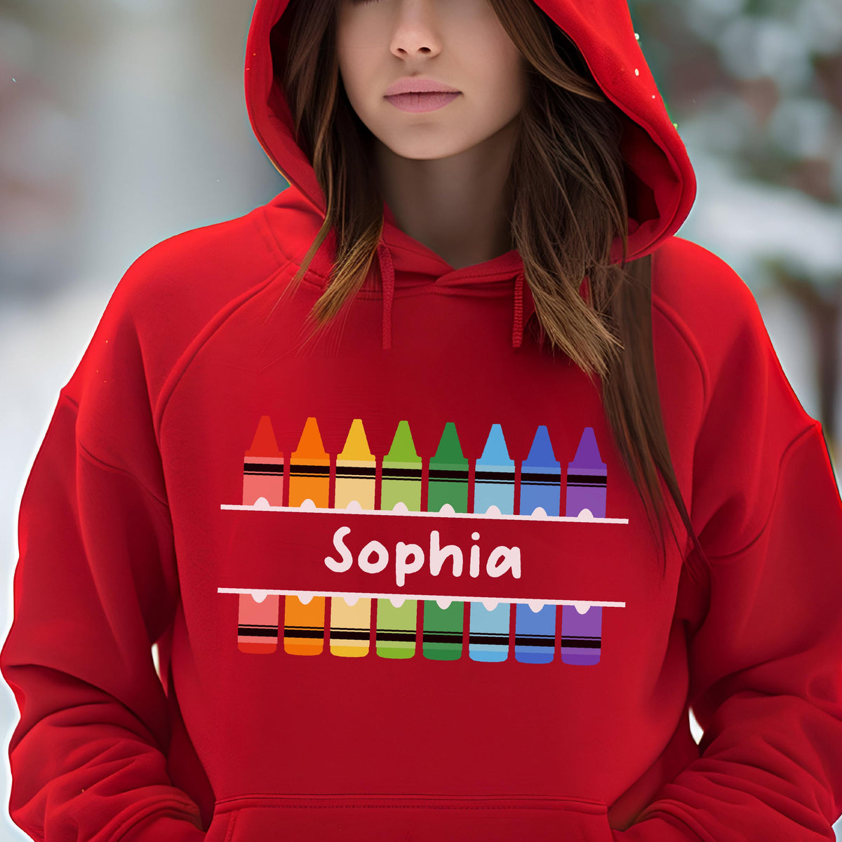 May include: A red hooded sweatshirt featuring a colorful crayon design. The design includes a row of crayons above and below the name "Sophia" in white. The sweatshirt is made of a soft material and has a hood.