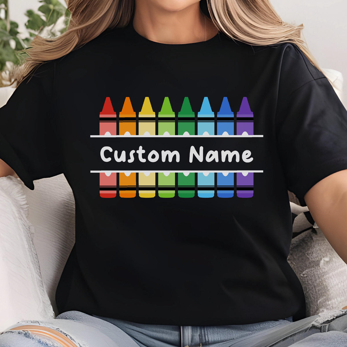 May include: Black t-shirt featuring a colorful crayon design in a rainbow spectrum. The design includes the text "Custom Name" in white, centered on the shirt. The crayons are arranged in two rows, creating a vibrant and personalized look.
