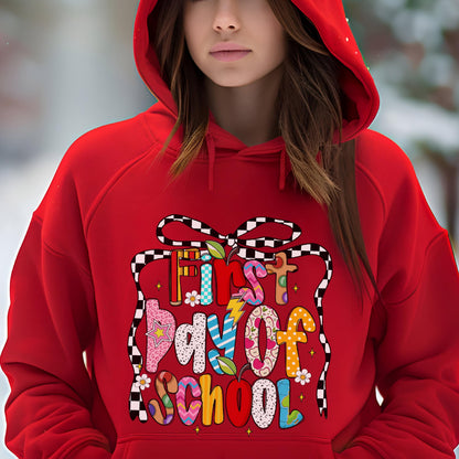 May include: A bright red hooded sweatshirt featuring a large graphic print on the front. The design includes the text First Day of School in colorful, patterned letters, framed by a black and white checkered ribbon graphic with small flowers.