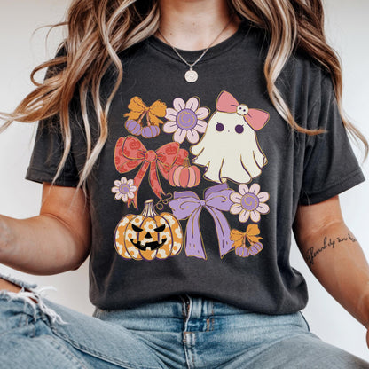 May include: Dark gray t-shirt featuring a Halloween-themed design. The design includes a ghost with a pink bow, pumpkins, bows, and flowers in shades of orange, pink, and purple. The shirt is made of a soft material.