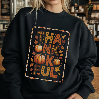 May include: Black sweatshirt with the word "THANKFUL" in a fall-themed design. The design includes pumpkins and autumn leaves in shades of orange, brown, and yellow, framed by a decorative border. A cozy and festive apparel item.