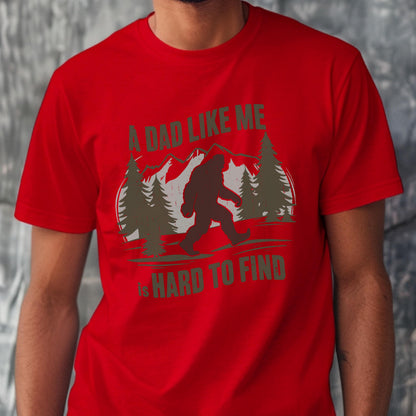 May include: A bright red short-sleeved t-shirt featuring a dark olive green graphic of a Bigfoot silhouette walking through a forest with mountains in the background. The text reads A DAD LIKE ME IS HARD TO FIND in olive green block lettering.