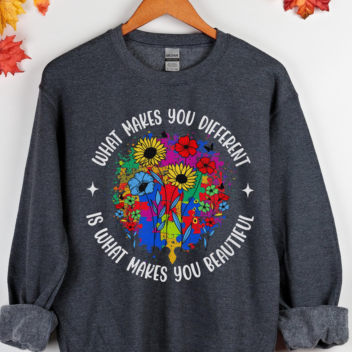 May include: Dark gray sweatshirt with the text "WHAT MAKES YOU DIFFERENT IS WHAT MAKES YOU BEAUTIFUL" in a circular design. The design features colorful flowers and paint splatters.