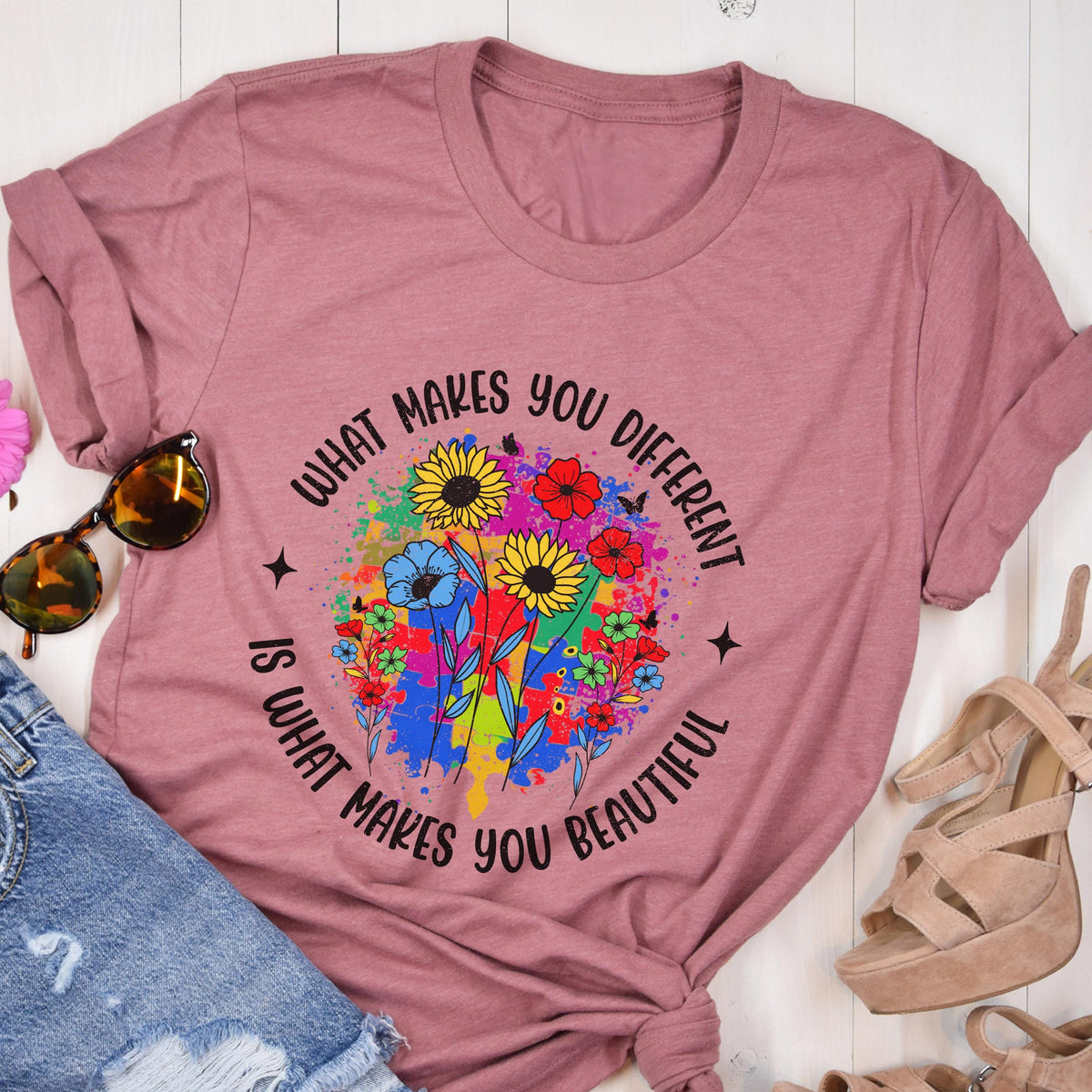 May include: Dusty rose t-shirt with a floral design and the text "What makes you different is what makes you beautiful." The design features colorful flowers and a paint splatter background.