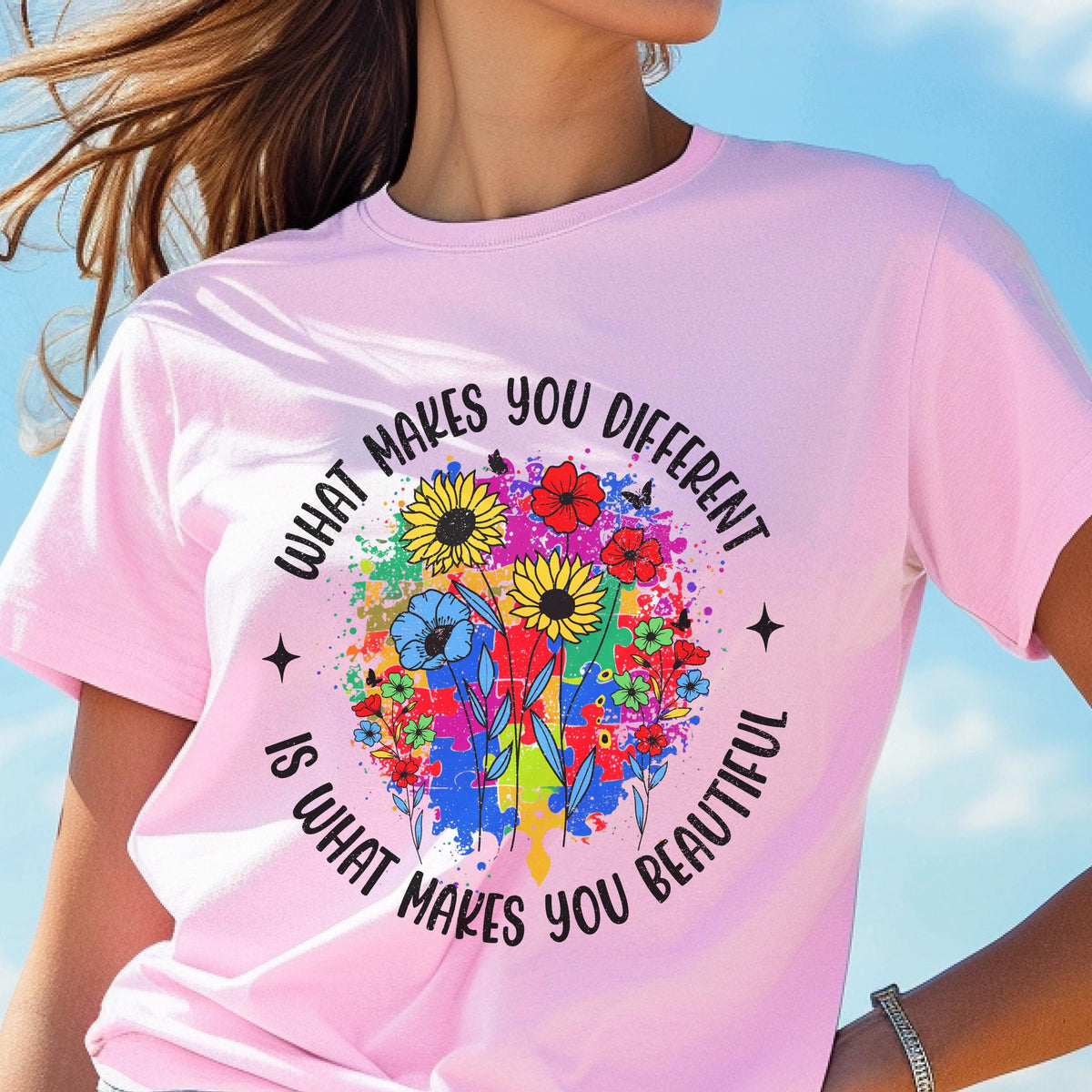 May include: A light pink t-shirt with the text "WHAT MAKES YOU DIFFERENT IS WHAT MAKES YOU BEAUTIFUL" encircling a colorful floral design. The design features sunflowers, blue flowers, and a splash of paint.