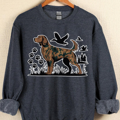 May include: A dark gray sweatshirt featuring a brown dog with a camouflage pattern, standing in grass. Black paw prints, birds, and trees are also in the design. The sweatshirt has rolled-up sleeves and a crew neck.