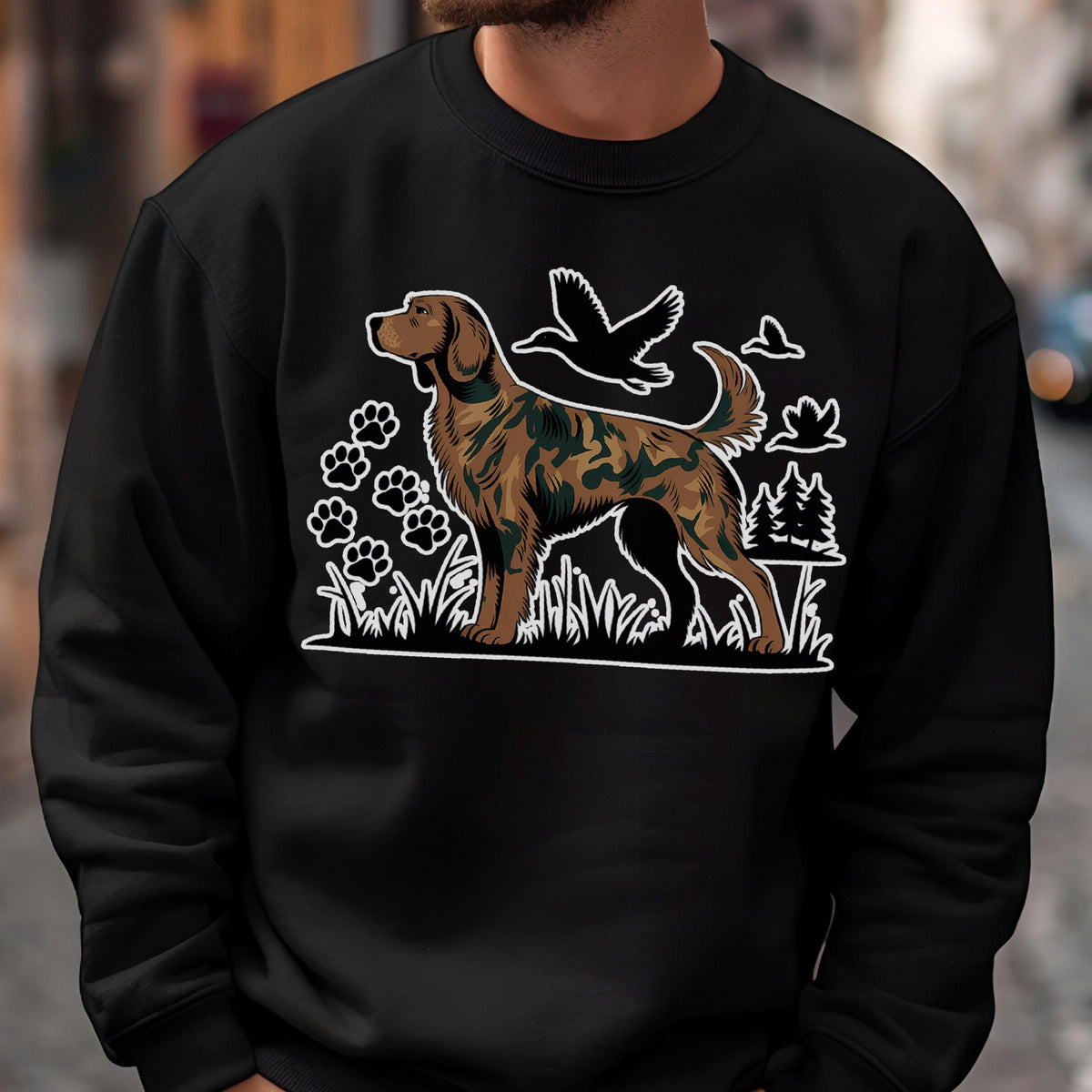 May include: Black sweatshirt featuring a brown and green dog illustration with a camouflage pattern. The design includes paw prints, birds, and trees in white outlines, creating a hunting or outdoors theme.
