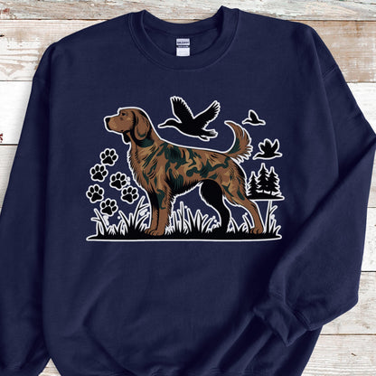 May include: Navy blue sweatshirt featuring a brown dog with a camouflage pattern, standing in grass. The design includes paw prints, birds, and trees. The dog is the central focus, with a white outline. The sweatshirt is a comfortable, casual style.