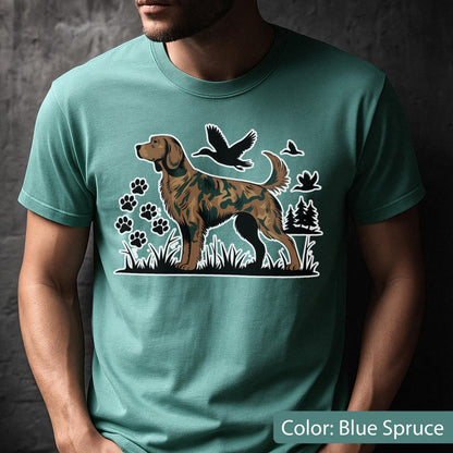 May include: A blue spruce crew neck t-shirt featuring a graphic print of a hunting dog with a camouflage pattern. The design includes black silhouettes of flying ducks, paw prints, and pine trees set against a grassy landscape background.