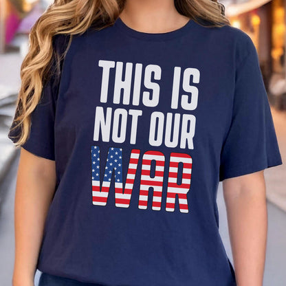 May include: Navy blue t-shirt with the text "THIS IS NOT OUR WAR" in white block letters. The word "WAR" is designed with the American flag's stars and stripes. The shirt has short sleeves.