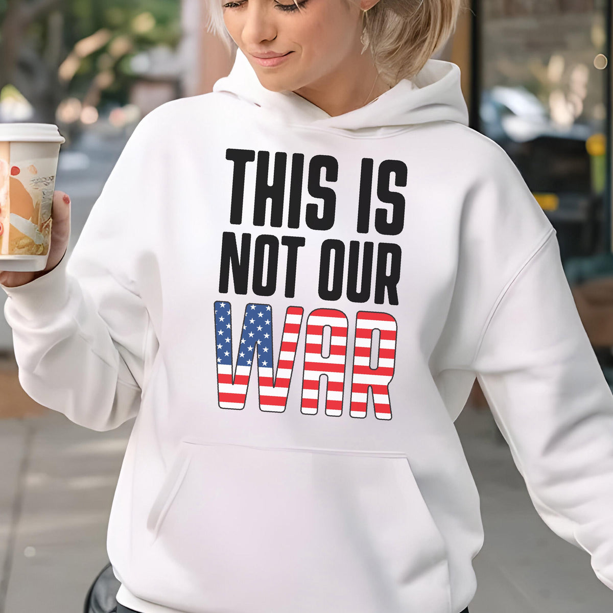 May include: White hooded sweatshirt with the text "THIS IS NOT OUR WAR" in black and red, white, and blue. The word "WAR" is designed with a pattern of red and white stripes and blue stars.