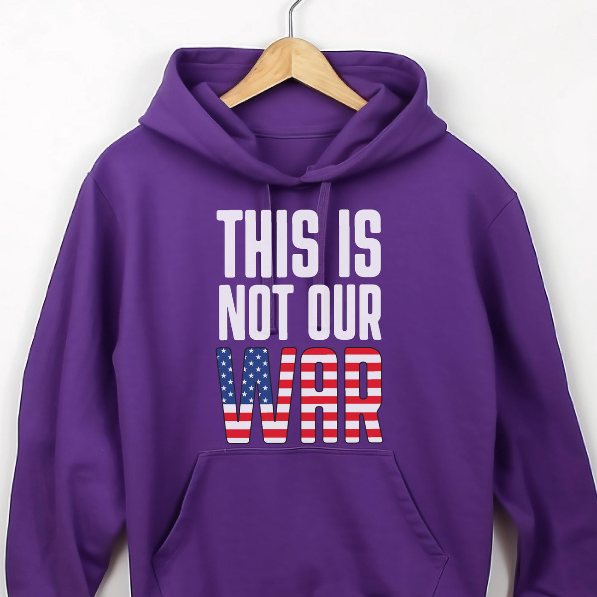 May include: A purple hoodie with the text "THIS IS NOT OUR WAR" in white block letters. The word "WAR" is designed with the American flag's stars and stripes.