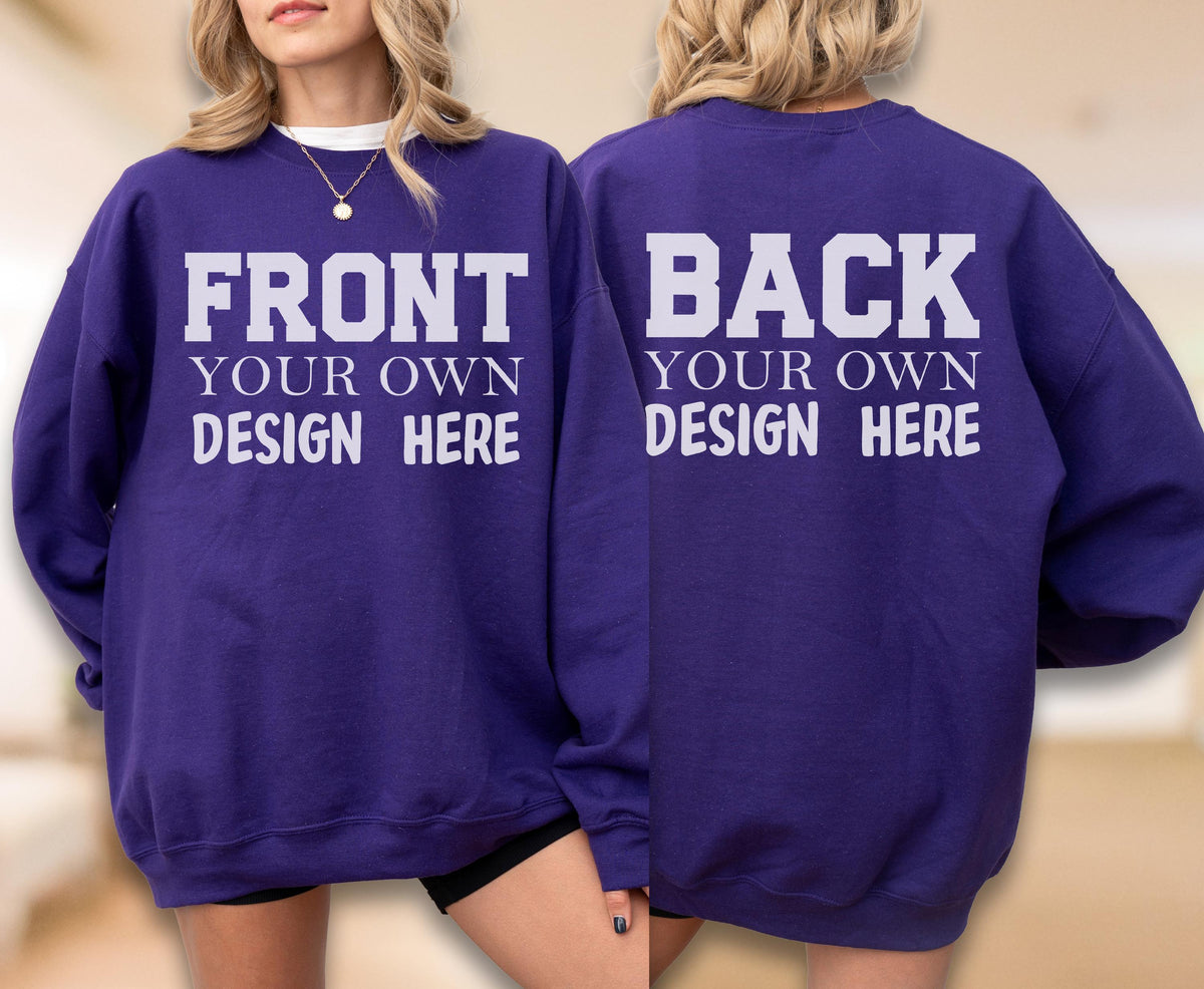 May include: A purple sweatshirt with white text on the front that reads "FRONT YOUR OWN DESIGN HERE." The back of the sweatshirt has the text "BACK YOUR OWN DESIGN HERE." The sweatshirt is a crew neck style.
