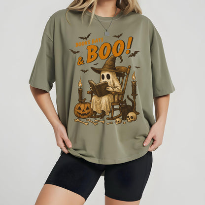 May include: Olive green t-shirt with a Halloween-themed graphic. The design features a ghost reading a book in a rocking chair, surrounded by bats, candles, a jack-o'-lantern, and the text "Books, Bats & Boo!"