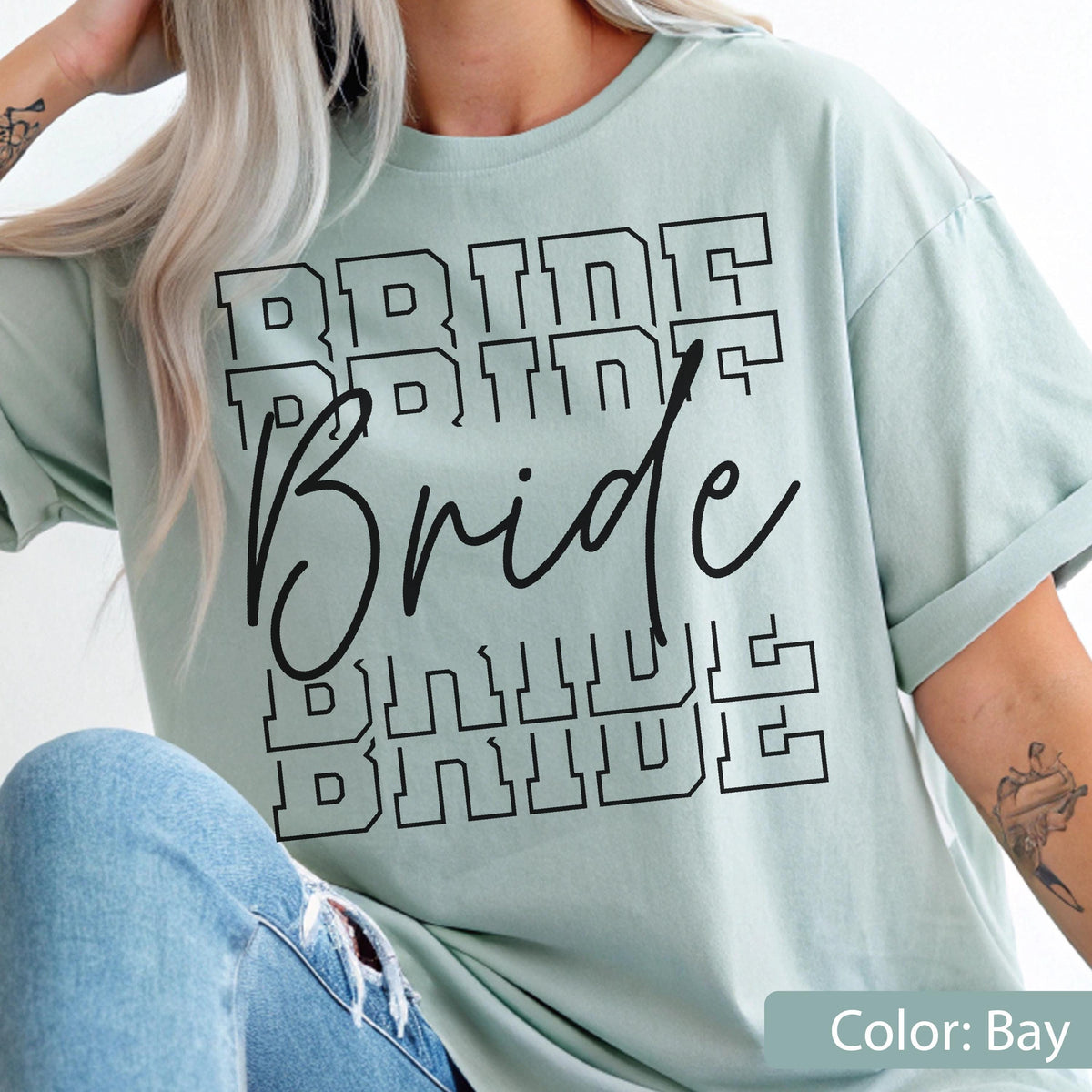 May include: A light green t-shirt with the word "Bride" in a black, bold, layered font. The word "Bride" is repeated multiple times in a stacked design. The shirt's color is labeled "Bay".