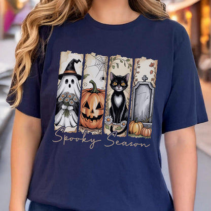 May include: A navy blue t-shirt featuring a graphic print of four vertical panels with Halloween imagery including a ghost in a witch hat holding flowers, a jack-o'-lantern, a black cat, and a tombstone, with the text Spooky Season below.