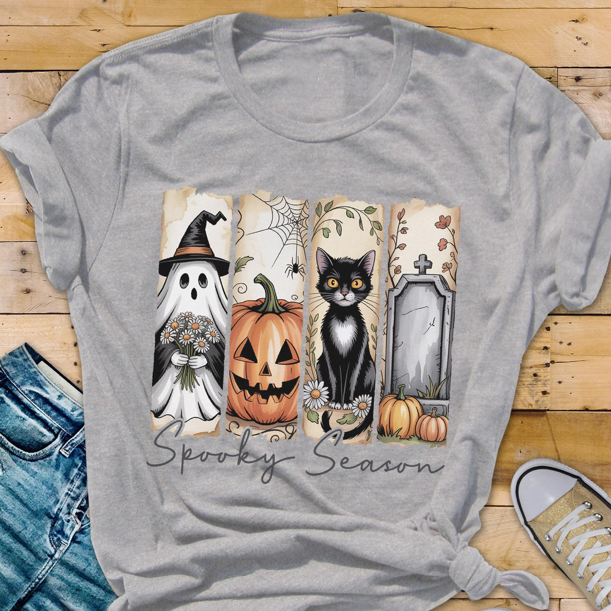 May include: A heather gray t-shirt featuring a graphic print of four vertical panels with Halloween imagery including a ghost in a witch hat, a jack-o'-lantern, a black cat, and a tombstone, with the text Spooky Season written below.
