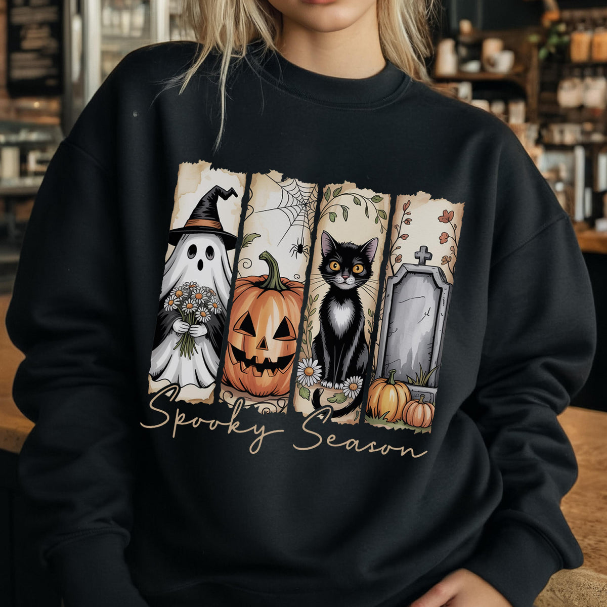 May include: A black crewneck sweatshirt featuring a graphic print of four vertical panels with a ghost in a witch hat, a jack-o'-lantern, a black cat, and a tombstone. The text Spooky Season is printed in a cursive script below the panels.
