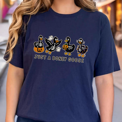May include: Navy blue t-shirt featuring a Halloween-themed graphic. The design includes four cartoon geese with skeleton details, holding pumpkins and accompanied by ghosts. The text "JUST A BONEY GOOSE" is printed below the geese in white.