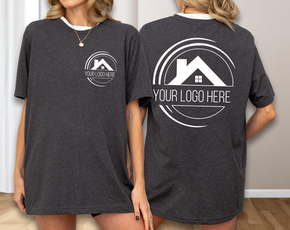 May include: Dark gray t-shirt with a white collar and a white logo featuring a house silhouette inside a circle. The text "YOUR LOGO HERE" is below the logo. The same logo is on the front and back of the shirt.
