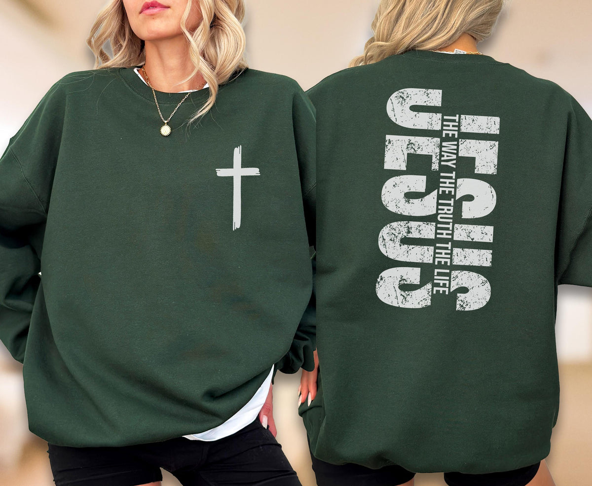 May include: Dark green sweatshirt with a white cross graphic on the front. The back of the sweatshirt features the word "JESUS" in large, distressed white letters, with the text "THE WAY THE TRUTH THE LIFE" stacked vertically above it. A casual, religious-themed garment.