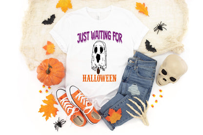 May include: White t-shirt with the text "JUST WAITING FOR HALLOWEEN" and a ghost graphic. The shirt is paired with blue jeans, orange sneakers, and Halloween decorations like a pumpkin and a skull.