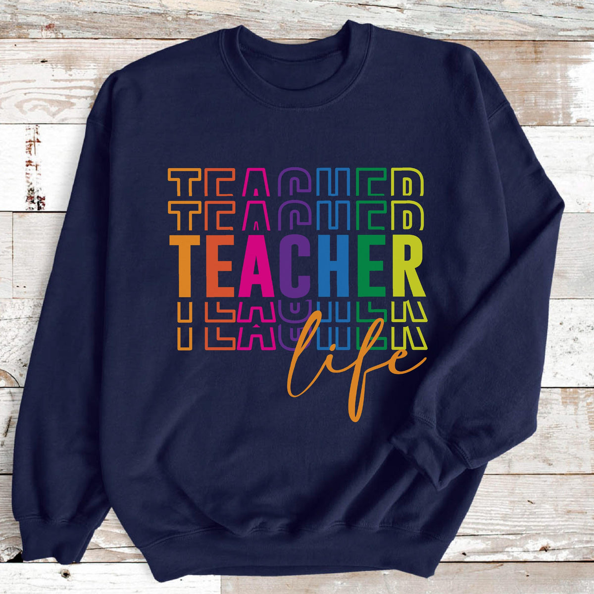 May include: A navy blue sweatshirt with the words "TEACHER" in a rainbow-colored stacked design. The word "life" is written in a cursive font below the word "TEACHER".