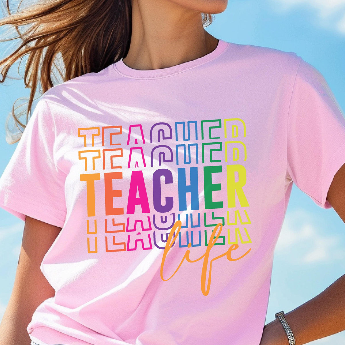 May include: A light pink t-shirt with the word "TEACHER" in a rainbow-colored, stacked design. The word "life" is written in a cursive, orange font below the word "TEACHER".
