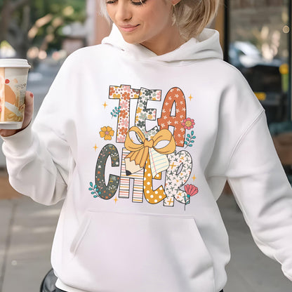 May include: White hoodie with the word "TEACHER" in a colorful floral and patterned design. The letters are decorated with flowers, a pencil, and a bow. The hoodie has a front pocket and a drawstring hood.