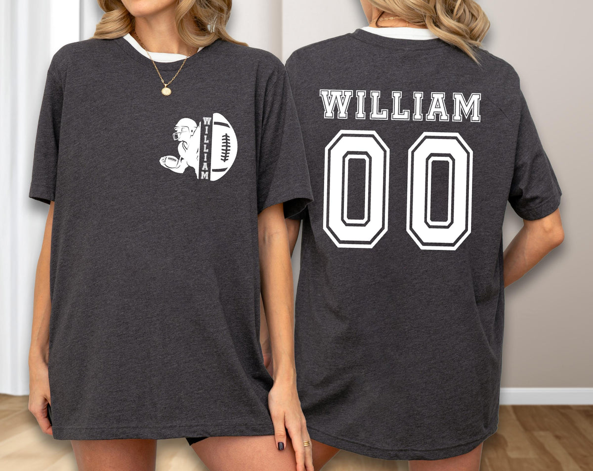May include: Dark gray t-shirt with white trim featuring a football design on the front and the name "WILLIAM" and the number "00" on the back. The football design includes a player and a football.