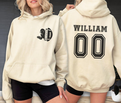 May include: A cream-colored hooded sweatshirt featuring a black graphic on the front left chest of a football player and a football with the name WILLIAM. The back displays the name WILLIAM in black block letters above the large black number 00.