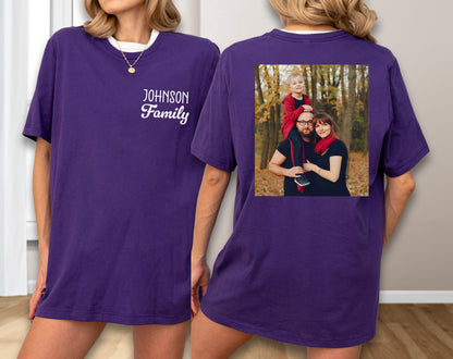 May include: A purple t-shirt with a white collar and the text "Johnson Family" in a script font. The back of the shirt features a family photo in a square frame. The photo shows a family of three in a forest setting.