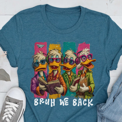 May include: Teal t-shirt featuring a cartoon illustration of four ducks wearing glasses and headphones, each holding a book. The ducks stand in front of colorful vertical stripes. The text "BRUH WE BACK" is printed below the illustration.